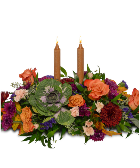 Thanksgiving centerpiece with orange roses, ornamental kale, burgundy mums, peach spray roses, greenery, fall leaves, and taper candles