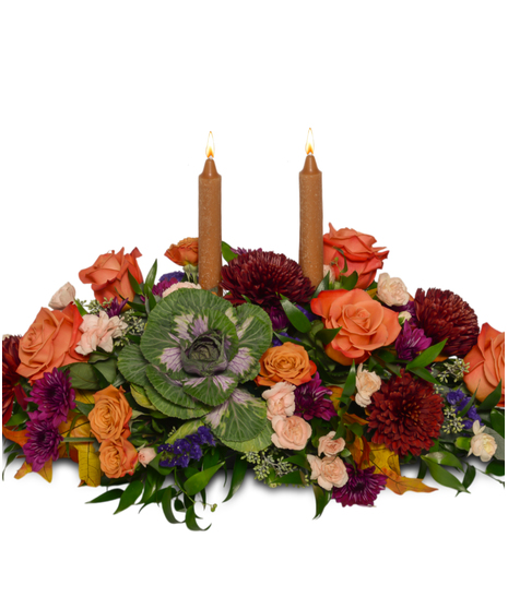 Thanksgiving centerpiece with orange roses, ornamental kale, burgundy mums, peach spray roses, greenery, fall leaves, and taper candles