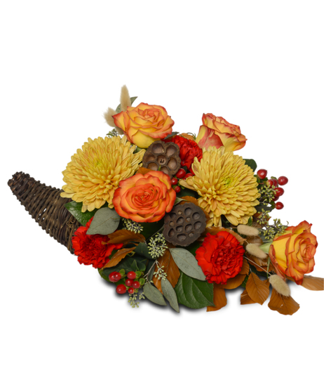 Thanksgiving cornucopia with bronze mums, orange roses, red carnations, lotus pods, berries, greenery, and autumn leaves in a woven horn of plenty basket