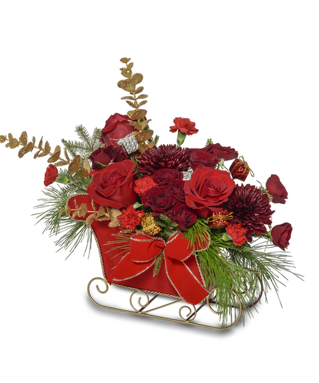 Red and gold Christmas sleigh arrangement with roses, carnations, mums, pine greenery, and festive ribbon in a decorative red sleigh container.