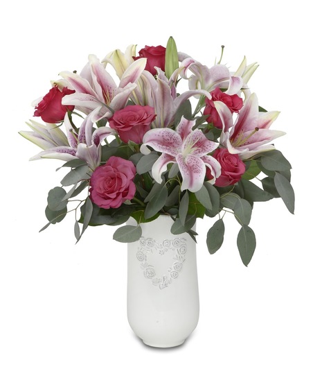 a white vase with a heart motif and pink roses and lilies 