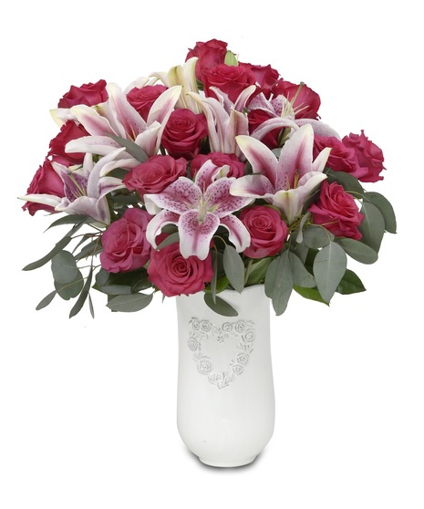 a white vase with a heart motif and pink roses and lilies 