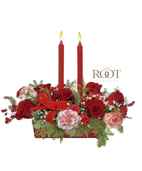 Red and white Christmas centerpiece with roses, peppermint carnations, evergreens, berries, velvet ribbons, and Root Candles in a white rectangular container.