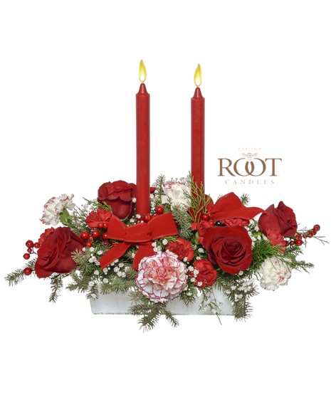 Red and white Christmas centerpiece with roses, peppermint carnations, evergreens, berries, velvet ribbons, and Root Candles in a white rectangular container.