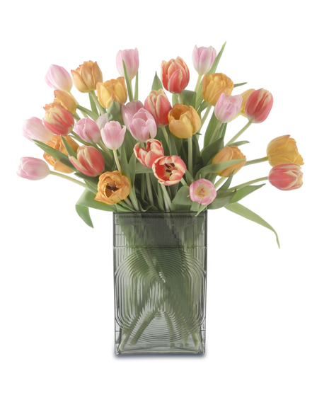 Colorful tulip arrangement in a textured glass vase featuring pink, coral, and yellow blooms with green foliage, styled in a loose, airy spring design.