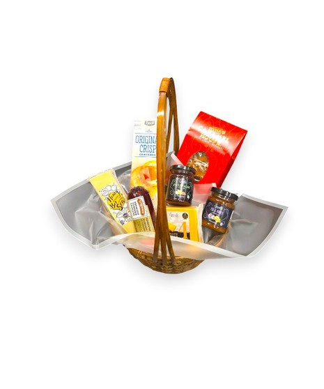 Wicker basket filled with gourmet foods including cheeses, salami, crackers, spreads, honey cheddar , and chocolate toffee arranged neatly for gifting.