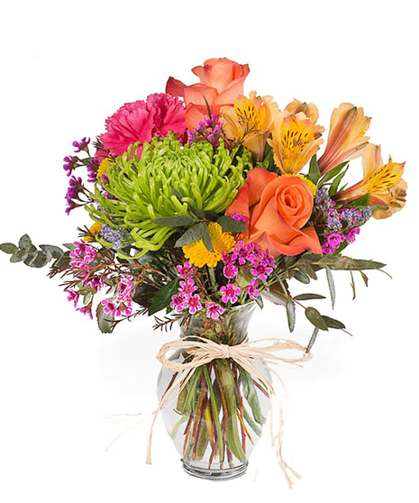 Vibrant mix of seasonal flowers and roses in a clear glass vase