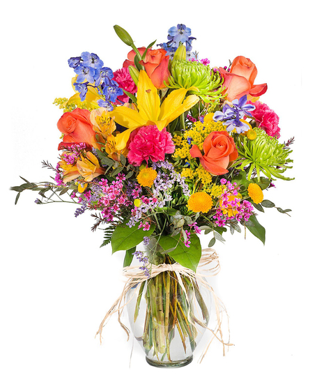 Vibrant mix of seasonal flowers and roses in a clear glass vase
