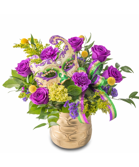 Mardi Gras floral arrangement with purple flowers, yellow accents, lush greenery, a decorative masquerade mask, and a purple, green, and gold ribbon in a gold vase.