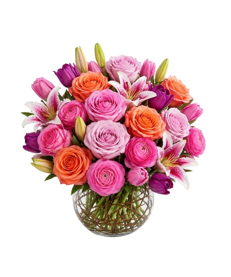 Luxury flower arrangement with pink roses, ranunculus, tulips, and stargazer lilies in a clear glass vase with twig accents
