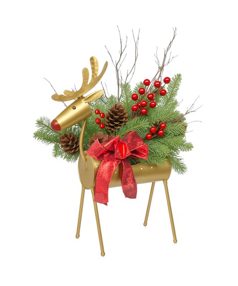 Golden reindeer container filled with pine branches, pinecones, red berries, twigs, and a red bow arranged as a festive Christmas decoration.