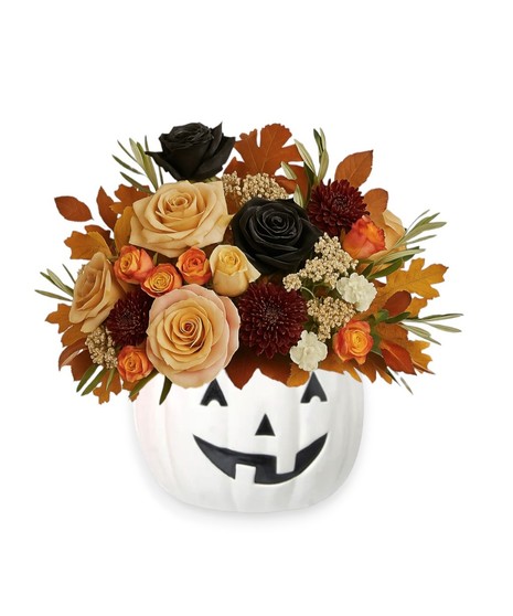 Elegant Halloween floral arrangement with black roses, peach and burgundy blooms, and fall leaves in a white jack-o’-lantern vase.