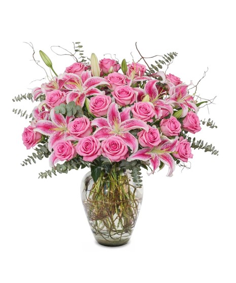 Pink Starfighter lilies arranged in a modern pink glass vase, with optional pink roses in deluxe, premium and exquisite sizes