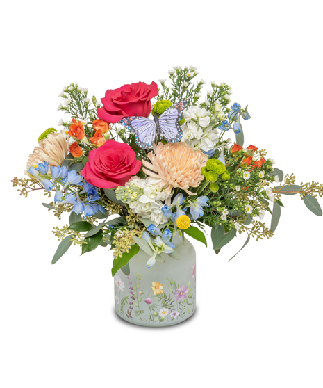 Frosted vase filled with vibrant roses, billy balls, delphinium, white Mardi Gras asters, and miniature roses, evoking the beauty of spring.