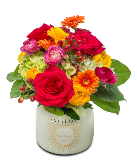 Two floral arrangements in white ceramic vases with golden sun design, filled with bright yellow, orange, and pink flowers. Available in two sizes.