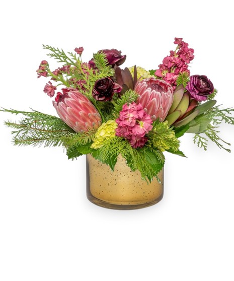Image of Snowberry floral arrangement: Cranberry, plum, and pink flowers with mink proteas, ranunculus, pink stock, green hydrangeas in a shimmering silver cylinder